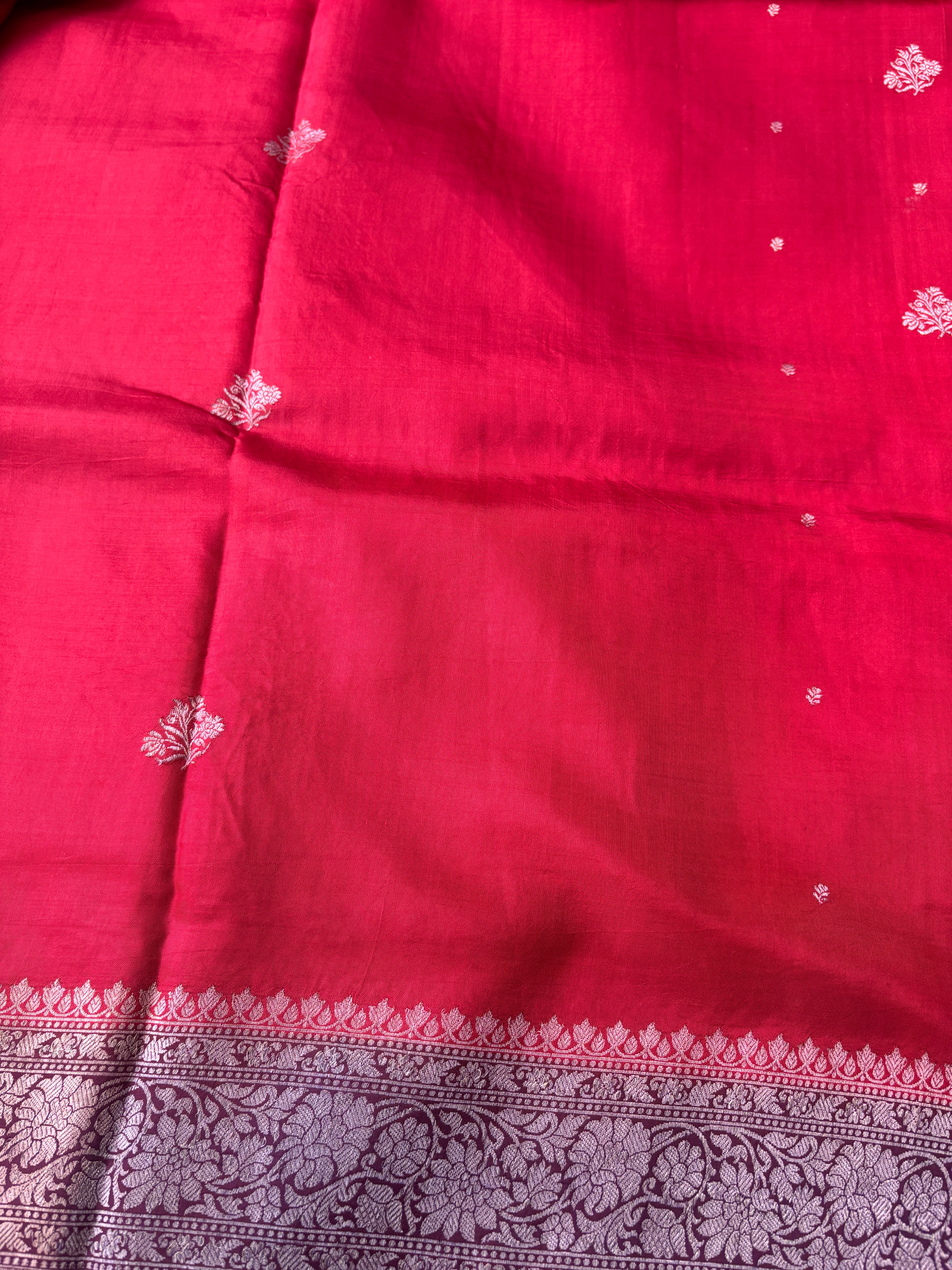 Close-up of intricate gold zari motifs on red pure silk fabric