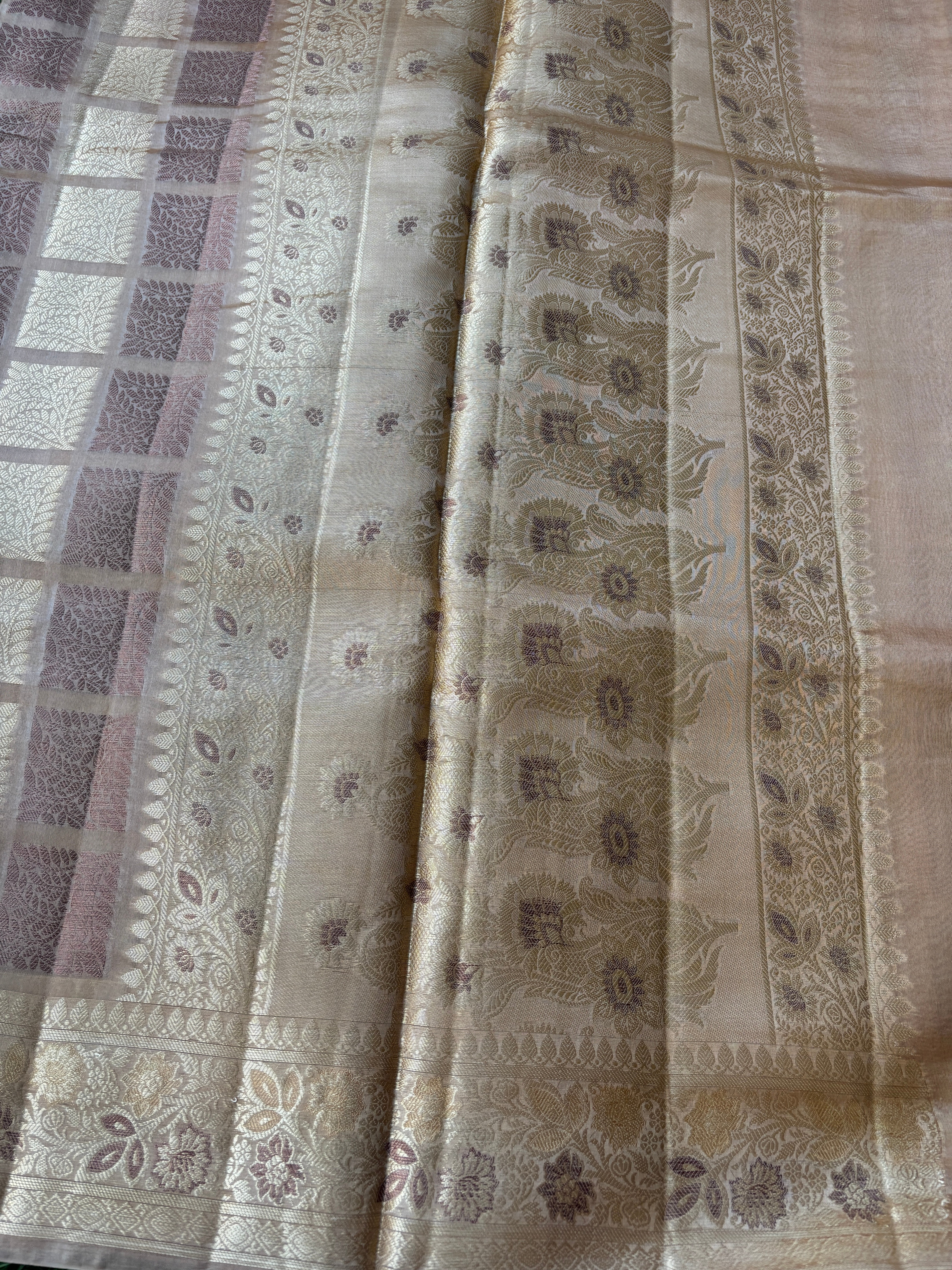 Close-up of intricate gold zari weaving on beige Banarasi silk fabric
