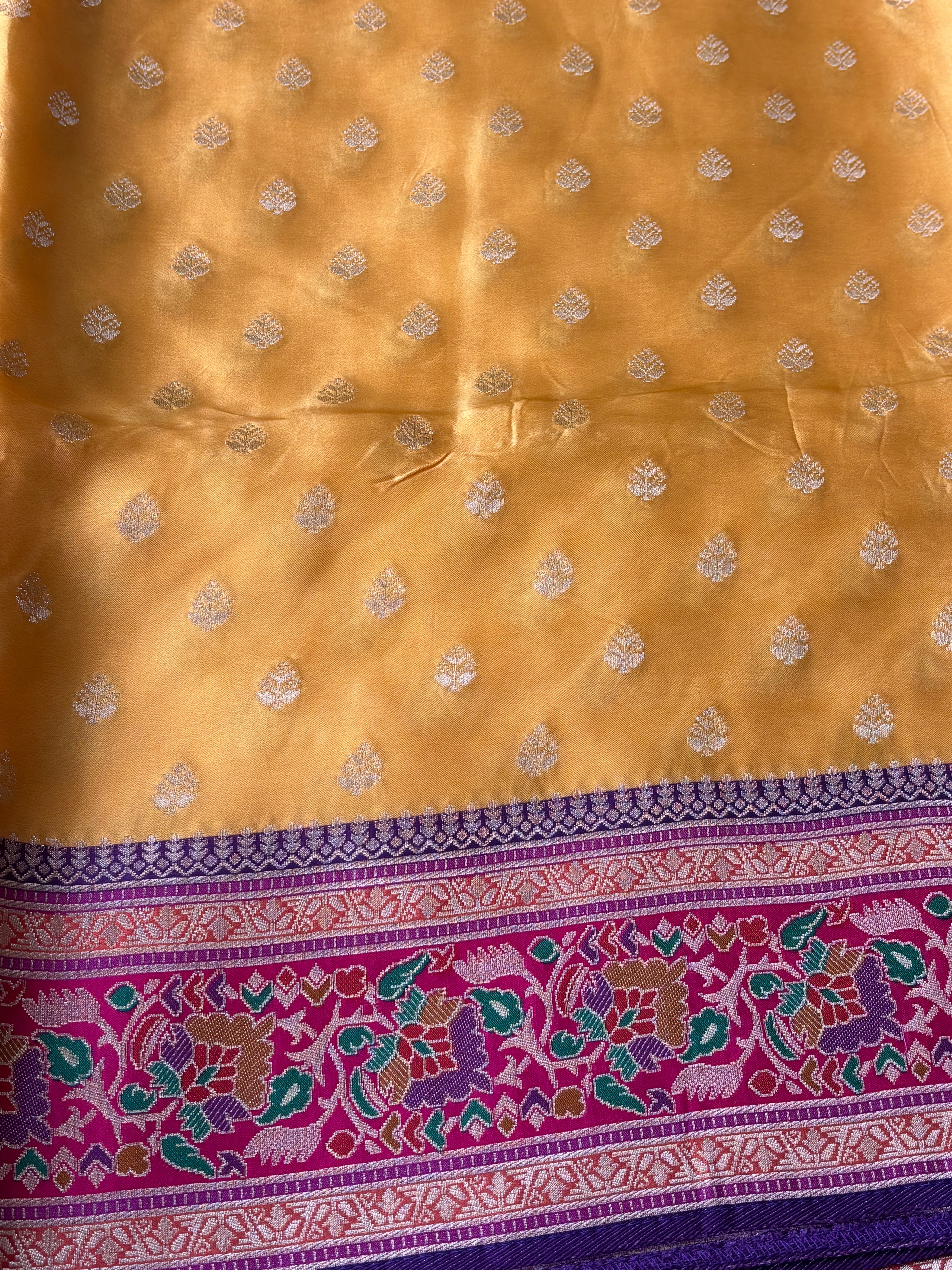 Close-up of intricate gold zari motifs on mango yellow Mashru silk fabric