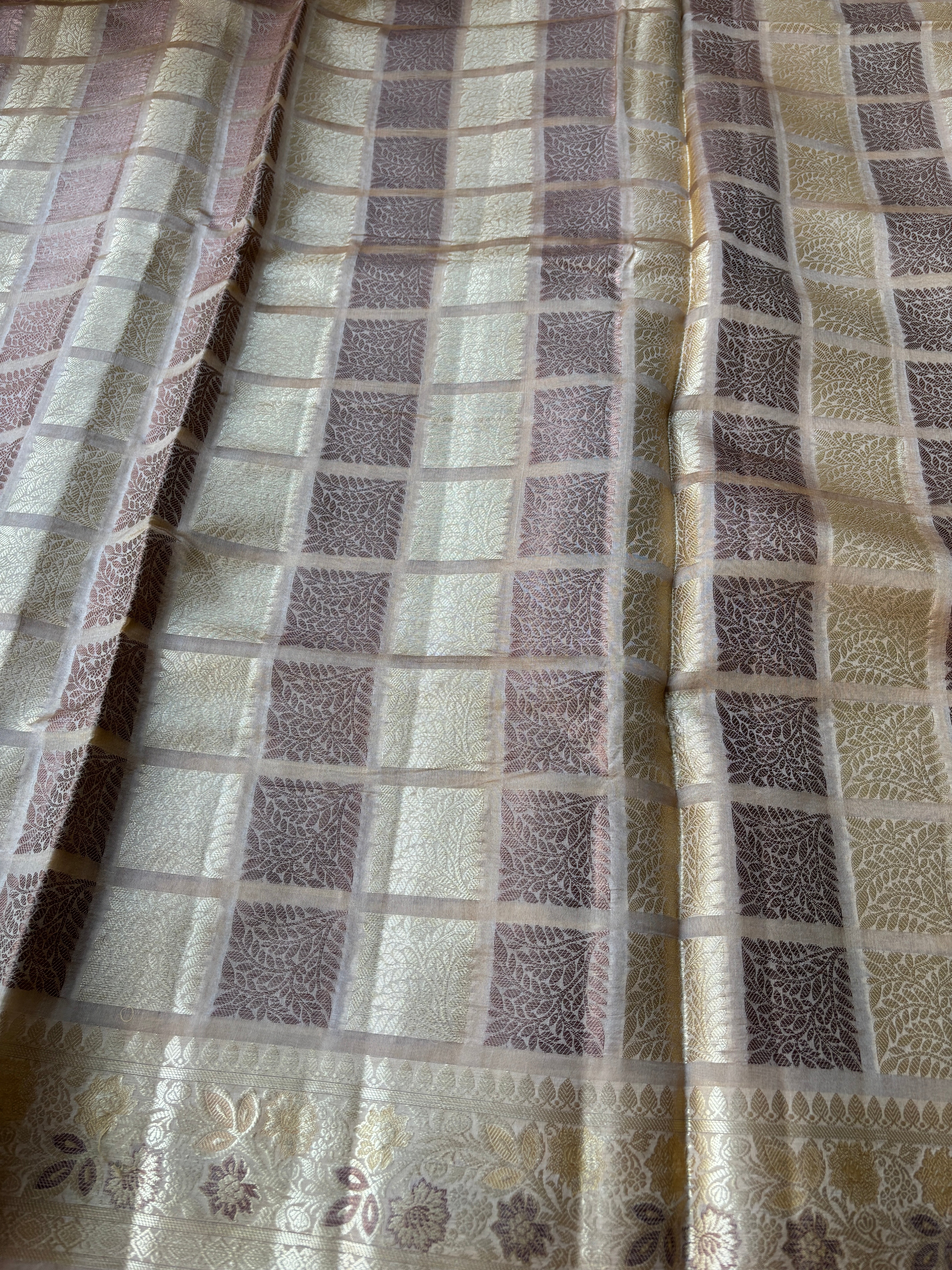 Close-up of intricate gold zari weaving on beige Banarasi silk fabric